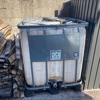 un grand conteneur métallique sur lequel est collé un autocollant, à côté d'un tas de bois