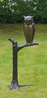 une statue représentant un hibou perché sur une branche d'arbre