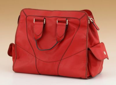 red leather handbag on a white surface with a beige background