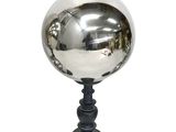 une boule argentée posée sur un socle noir, sur fond blanc