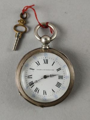 a silver pocket watch with a key attached to it
