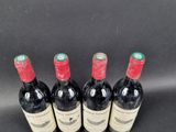 four bottles of red wine are lined up on a black surface