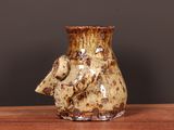 a brown vase sitting on a table with a black background