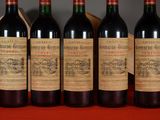 six bottles of red wine are lined up on a table