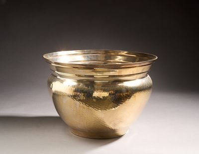 a gold bowl sitting on a table with a black background