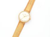 a close up of a gold watch on a white surface