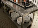 une grande table en acier inoxydable dans une cuisine, sur laquelle sont posés des plats