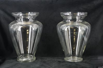 une paire de vases en verre transparent posés sur un fond noir