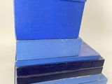 three blue boxes stacked on top of each other on a white surface