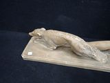 statue of a cat laying on a stone slab on a black background