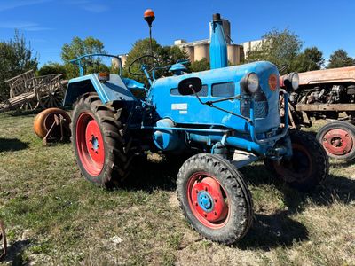 un tracteur bleu garé dans l'herbe