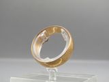 a gold ring sitting on top of a clear stand