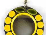 un gros plan d'un pendentif circulaire jaune et noir orné d'une perle jaune