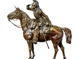 statue en bronze représentant un homme à cheval, posée sur une table en marbre