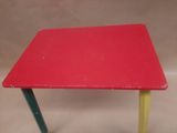 a small table with a red top and yellow legs