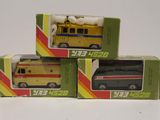 trois boîtes contenant des ambulances miniatures, posées sur une surface blanche