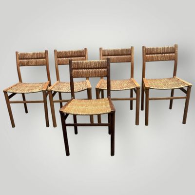 quatre chaises en bois avec des assises tressées, alignées sur un fond blanc