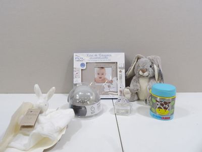 une photo représentant un biberon, un cadre photo et une peluche posés sur une table