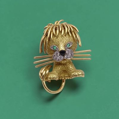 une image représentant une broche en forme de chat en or, avec des yeux en diamant