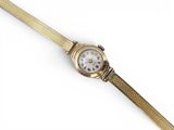 gros plan d'une montre-bracelet en or sur une surface blanche