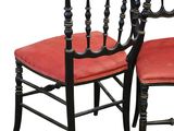pair of black painted chairs with red upholstered seats