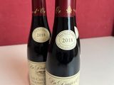 two bottles of wine sitting on a table next to each other