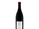 the bottle of red wine is sitting on a white surface