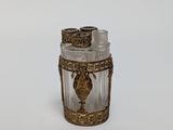 an image of a small glass jar with a gold decoration on it