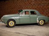 a small green car parked in front of a brick wall