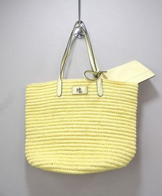 yellow straw tote bag hanging from a hook on a wall