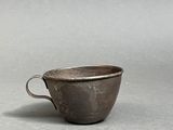 a small cup sitting on top of a table next to a white wall