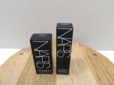a pair of nars lipsticks sitting on top of a wooden table