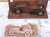 Des sculptures représentant des voitures anciennes sont exposées sur un socle en marbre