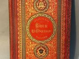 an old book with a red cover sitting on top of a table