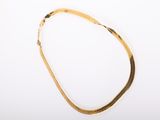 a close up of a gold necklace on a white surface