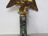 une statue d'aigle posée sur un socle en marbre