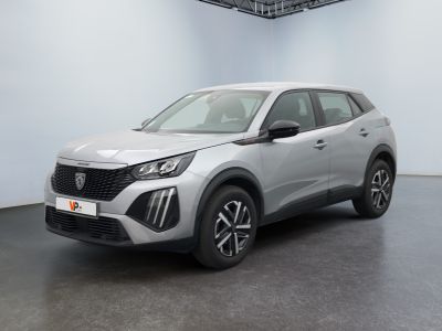 Une voiture argentée est garée dans une grande pièce au sol noir.