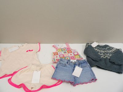several children ' s clothes are lined up on a white table