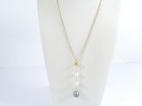 a white mannequin with a gold chain and a blue stone pendant