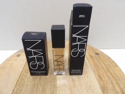 trois produits de beauté Nars posés sur une table en bois