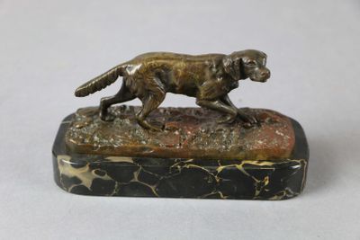 statue d'un chien en train de courir, posée sur un socle en marbre, sur une surface blanche