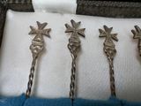 three silver spoons with star decorations on them sitting on a white cloth