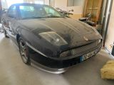 a black car that is in a garage with other cars in the background