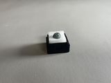 un gros plan d'un petit objet noir et blanc posé sur une surface blanche