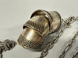 a silver object with a chain around it on a table