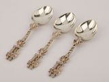 three silver spoons and a spoon with handles on a white surface