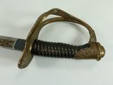 a sword with a gold handle on a white surface