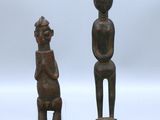 deux sculptures en bois représentant un homme et une femme assis sur un tabouret
