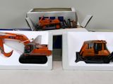 deux boîtes contenant chacune une petite pelleteuse et une boîte contenant un petit bulldozer