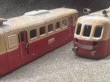 two toy trains sitting side by side on the ground